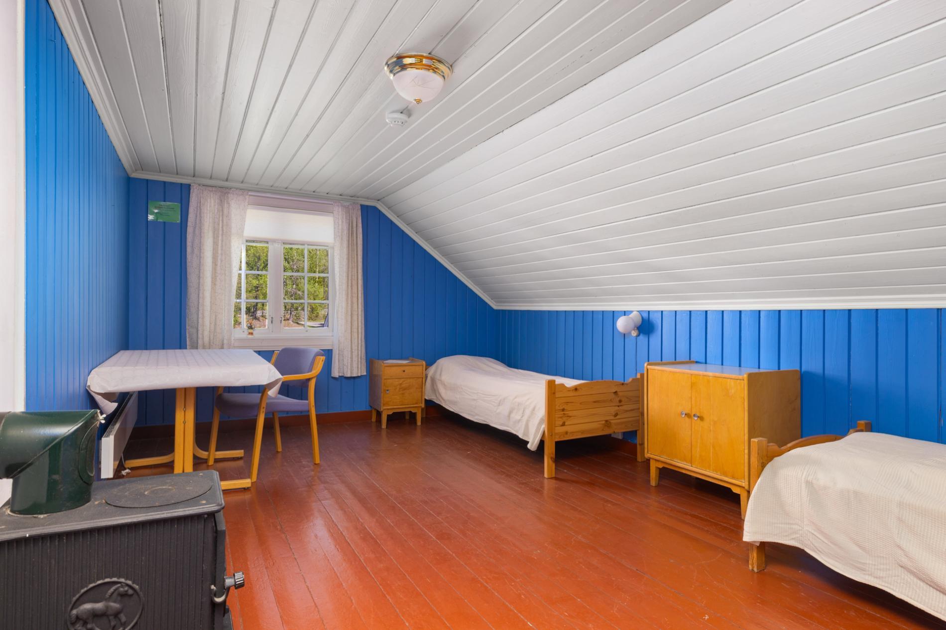 Soverom på loftet i Kvitehuset med blå vegger og tre senger