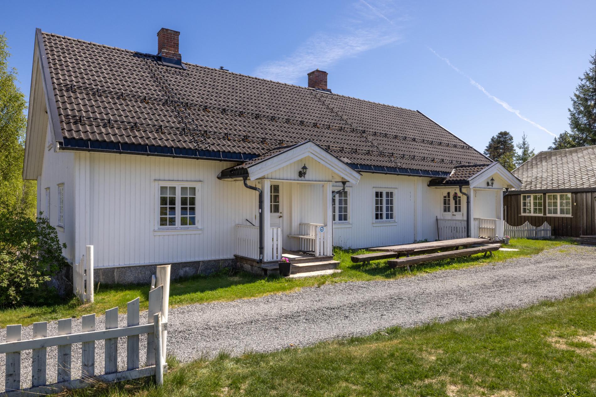 Kvitehuset, et hvitt trehus med teglstak og hvitt stakittgjerde på tunet på Malungen Gjestegård